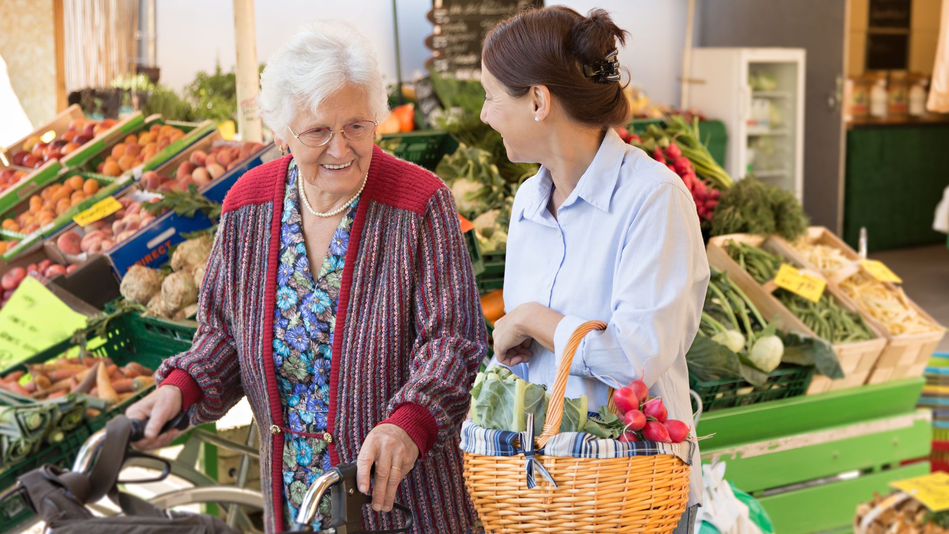 daughter and elderly mother with walker in fruit shop