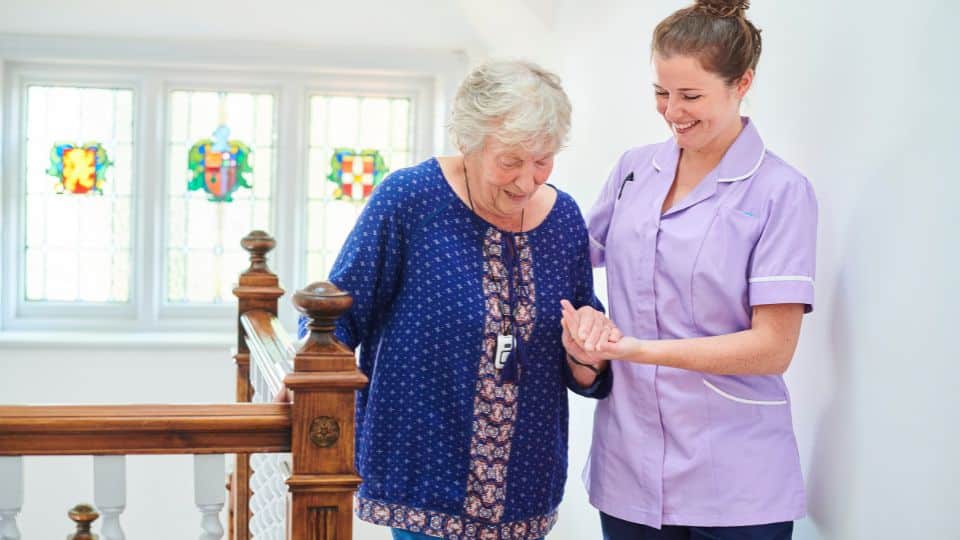 female care professional assisting elderly women walk