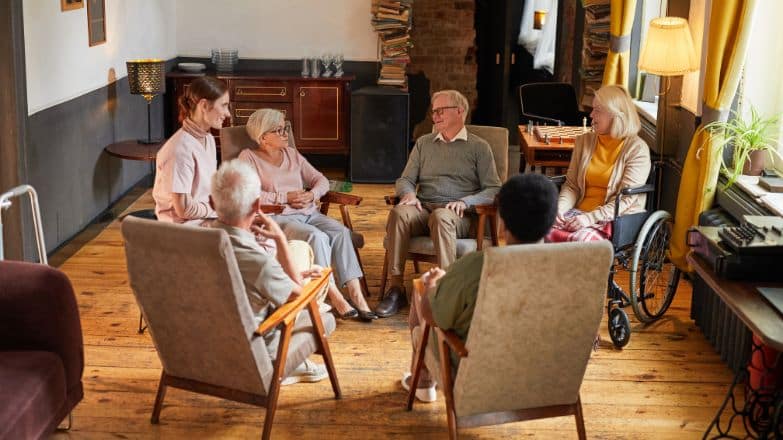 4 Elderly people sitting in a circle of chair with a professional caregiver