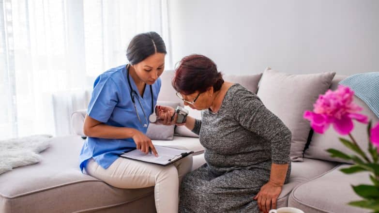 professional caregiver showing report to an elderly women sitting on a lounge chair