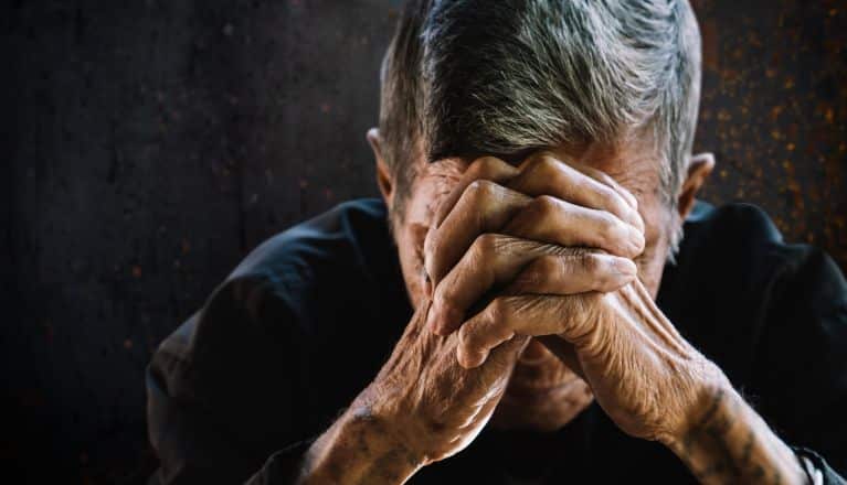 Elderly man with his head in his hands